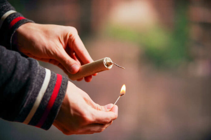 Close,Up,Of,Man,Hand,Lighting,Up,A,Firecrackers,In