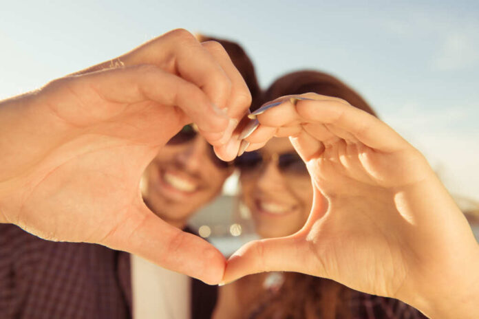 Happy,Romantic,Couple,In,Love,Gesturing,A,Heart,With,Fingers