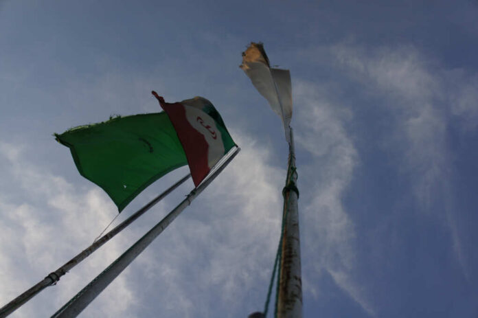 Iran's,Flag,With,The,Background,Of,Sky,And,A,Green