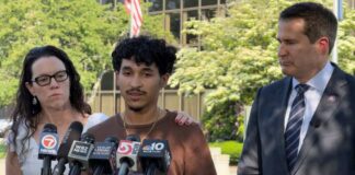 Individuals at a press conference with microphones and cameras present