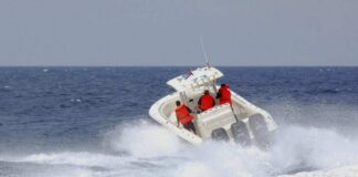 A speedboat with passengers navigating through rough ocean waves
