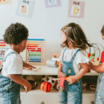 Vermont’s CATASTROPHIC Decline Three children engaged in play with educational toys in a colorful classroom