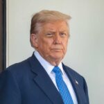 Texas Primaries Shaken by Trump’s Endorsements A man in a suit with a serious expression standing outdoors