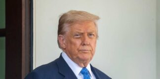 A man in a suit with a serious expression standing outdoors