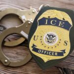Biden Judge SLAMS Trump ICE Raids ICE officer badge next to handcuffs on a wooden surface