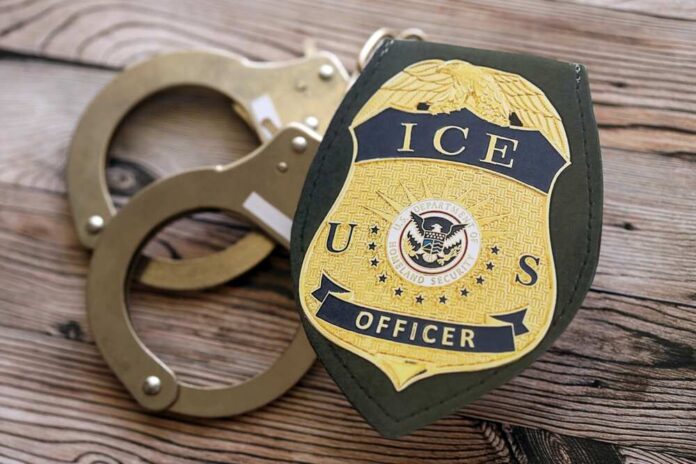 shutterstock_2704937373 (1).jpg ICE officer badge next to handcuffs on a wooden surface