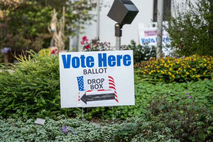 shutterstock1837548700jpg Sign indicating where to vote with a ballot drop box