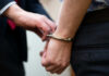 A close-up of a person being handcuffed by an officer