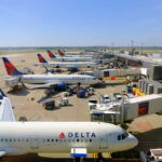 Washington Shutdown: Smaller Airports Face Closure View of multiple Delta Airlines planes parked at an airport terminal with ground crew and vehicles