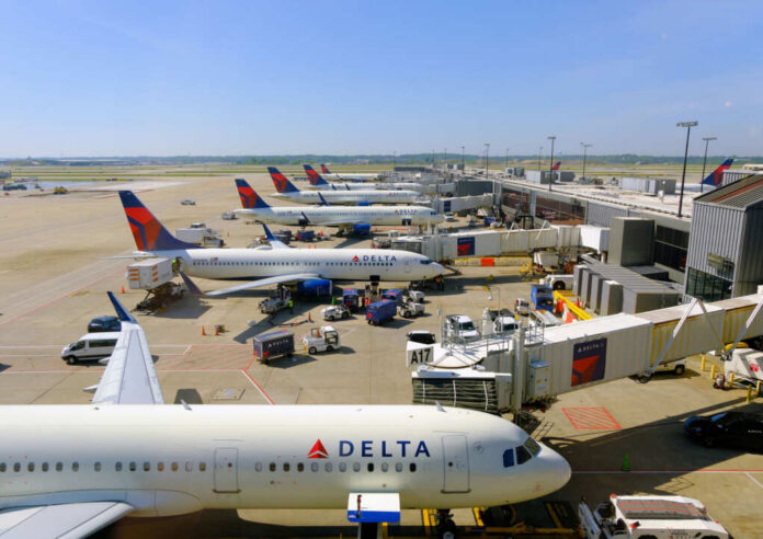 View of multiple Delta Airlines planes parked at an airport terminal with ground crew and vehicles