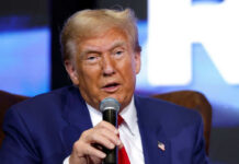 A man in a blue suit speaking into a microphone