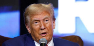 A man in a blue suit speaking into a microphone