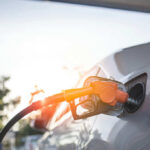 Gas Prices SKYROCKET – Pain at the Pump! A fuel nozzle inserted into a cars gas tank during sunset