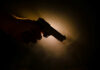 Silhouette of a hand holding a handgun against a dramatic light background