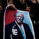 Massive Iran Standoff: Trump’s Tough New Terms A person holding a protest sign featuring a stylized illustration of a man with a serious expression