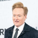 BRUTAL Oscars Moment Exposes Hollywood’s Darkest Fear A man with styled hair smiling at a media event