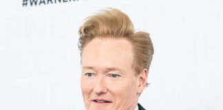A man with styled hair smiling at a media event
