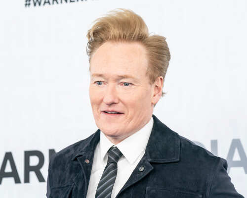 A man with styled hair smiling at a media event
