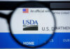 Close-up view of the USDA website logo through a magnifying glass