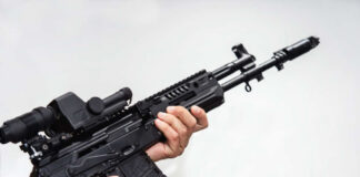Person holding an AK-47 rifle with a scope