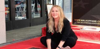 A woman kneeling on the Hollywood Walk of Fame next to a star