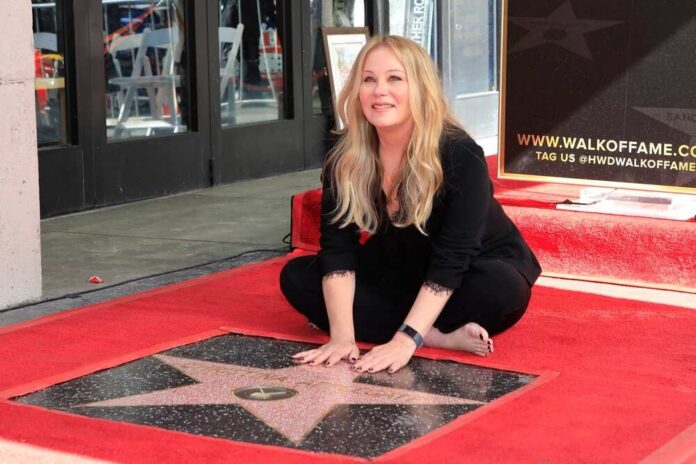 shutterstock_2237928597.jpg A woman kneeling on the Hollywood Walk of Fame next to a star