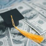 Critics Furious as Trump TRANSFERS $1.7 Trillion Loans A graduation cap placed on a pile of hundred dollar bills
