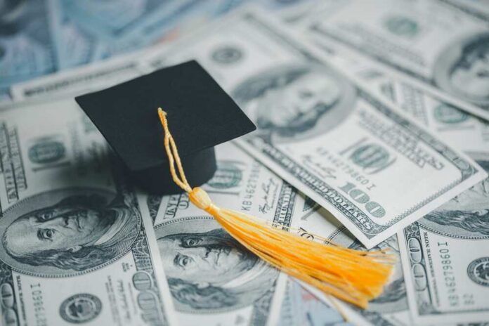 A graduation cap placed on a pile of hundred dollar bills