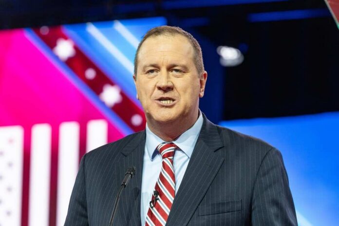 shutterstock_2269916593.jpg A man in a suit speaking at a podium during a conference
