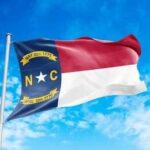 North Carolina state flag waving against a blue sky