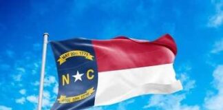 North Carolina state flag waving against a blue sky
