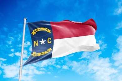 North Carolina state flag waving against a blue sky