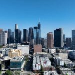 Is California’s Economy COLLAPSING? Shocking Details Aerial view of a city skyline with tall buildings under a clear blue sky