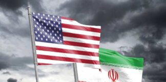 Flags of the United States and Iran waving against a cloudy sky