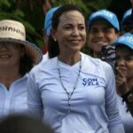 María Corina Machado smiling at a political rally surrounded by supporters