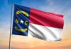 North Carolina state flag waving against a sunset sky