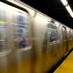 NYC Subway Horror: Hero Veteran’s Tragic End A subway train in motion at a station with blurred reflections