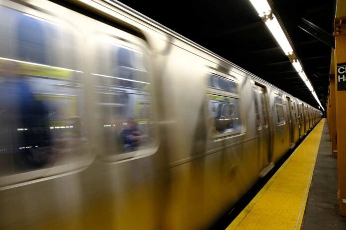 A subway train in motion at a station with blurred reflections