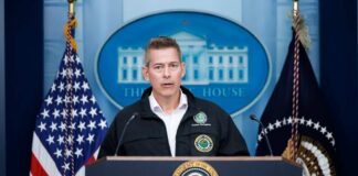 Government official speaking at a podium during a press conference at the White House