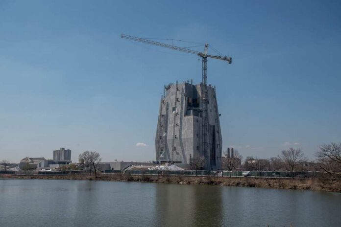 A large construction site with a crane and a partially completed building near a body of water