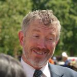Massie Battles Trump’s Loyalty Demands in Epic Clash A smiling man in a suit engaging in conversation outdoors
