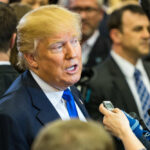 Trump Sparks Record Fundraising Amid Iran War Woes A man speaking to reporters at a press event surrounded by media personnel
