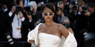 A celebrity posing on the red carpet at an event, surrounded by photographers