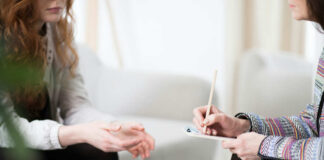 Two individuals engaged in a counseling session, one taking notes