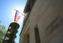 The Department of Justice building with an American flag and sunlight in the background
