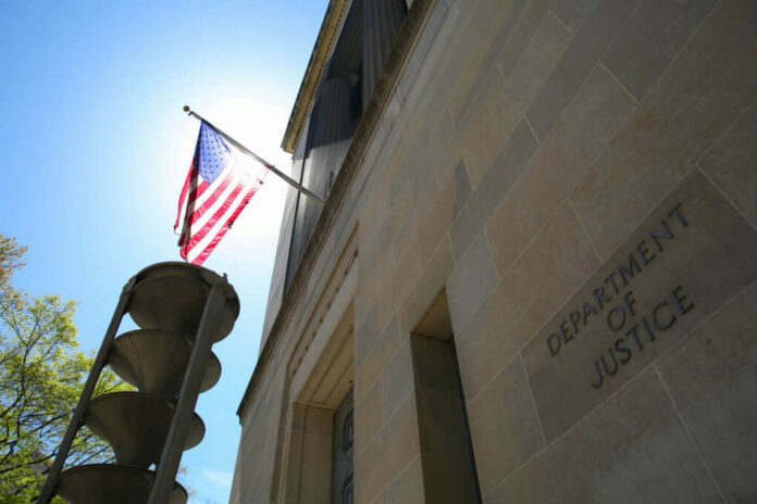 The Department of Justice building with an American flag and sunlight in the background