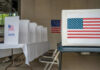 Voting booth with American flag and ballot box in a polling station