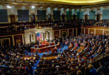 DHS Workers UNPAID — Lawmakers Live It Up! A large gathering of officials in a congressional chamber during a legislative session
