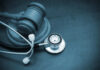 A wooden gavel next to a stethoscope on a dark surface