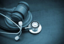 A wooden gavel next to a stethoscope on a dark surface